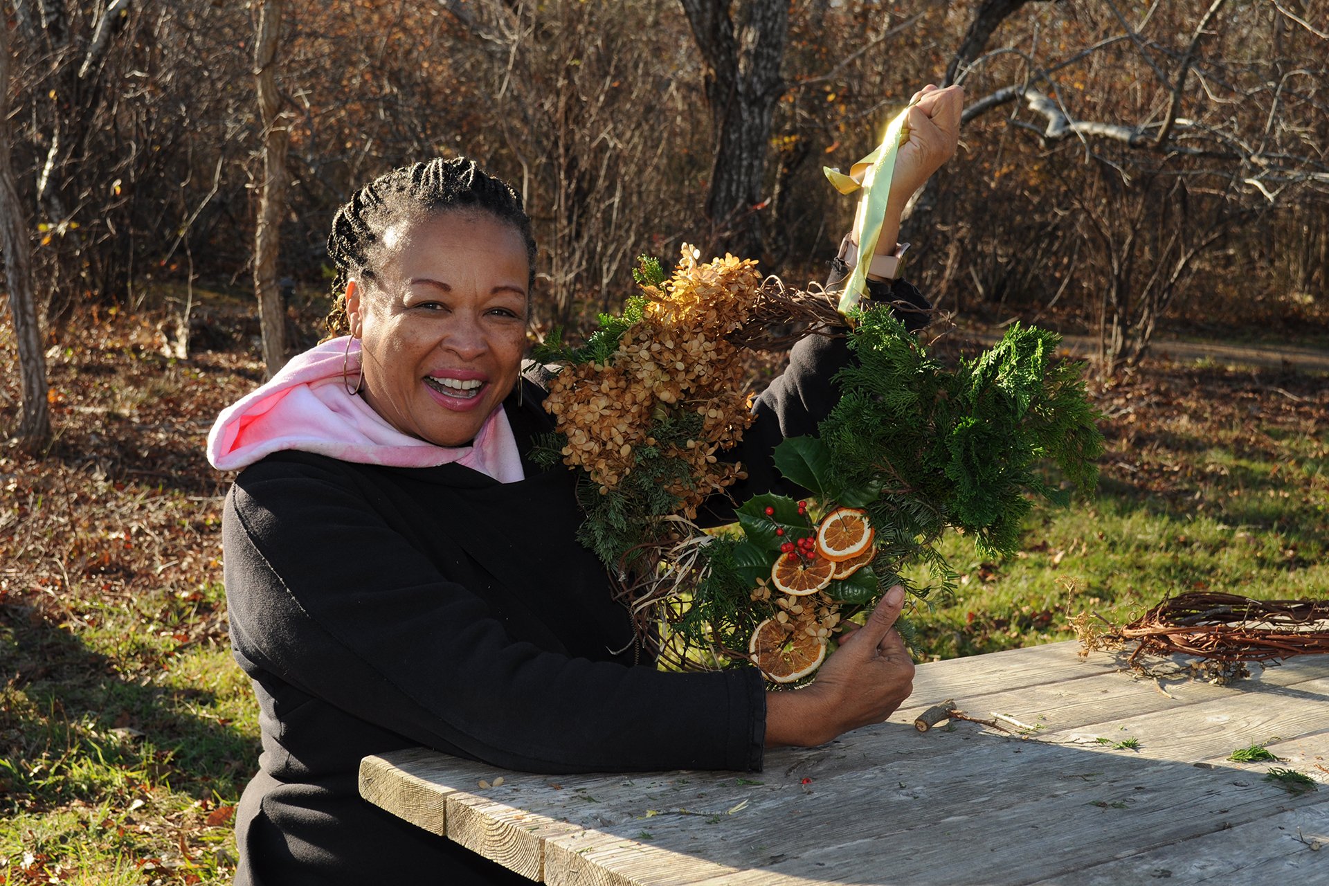 A woman seated at a table, showing off a fall-themed wreath