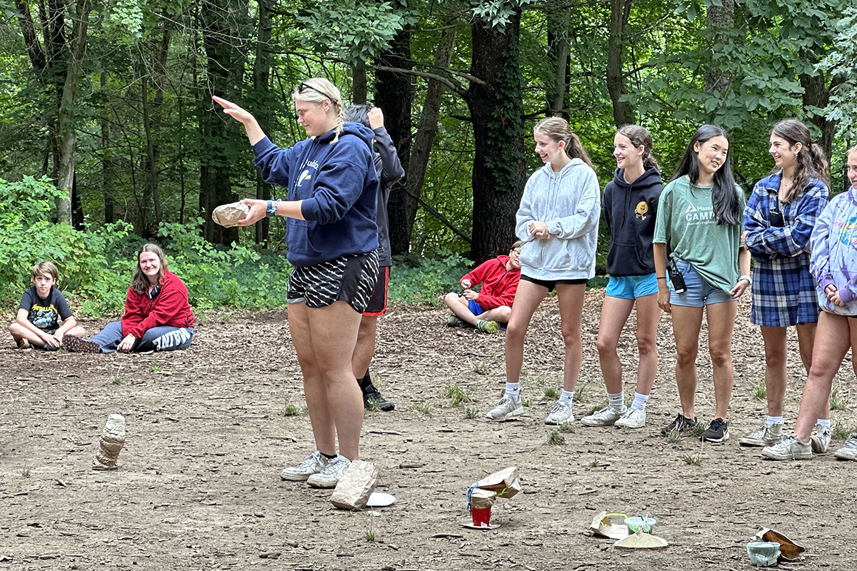 Camp counselor dropping an egg with teens behind her