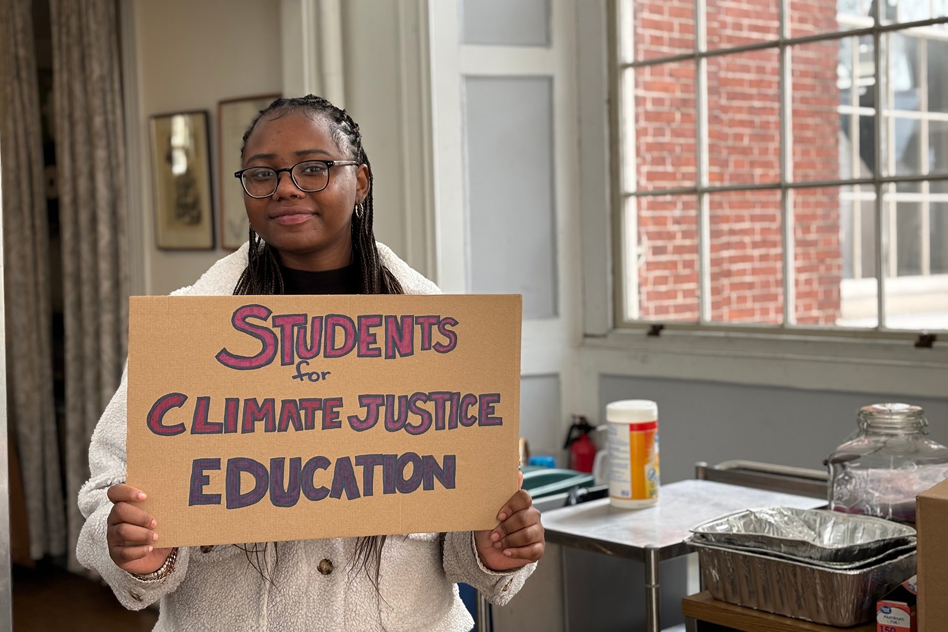 Ari Iriganeza holds a sign at youth climate lobby day on Beacon Hill.