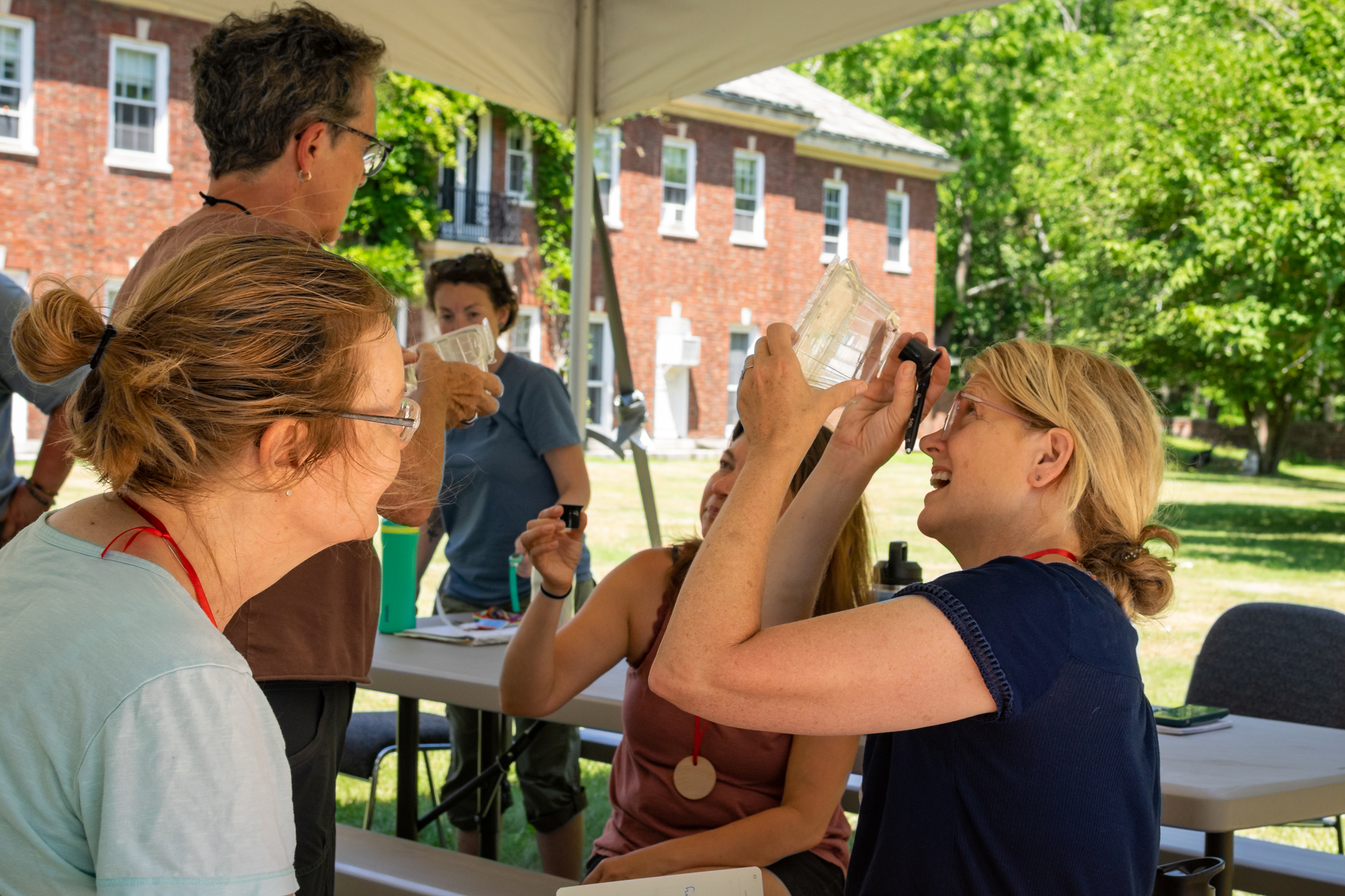 Educator looking up into a container with a magnifying glass