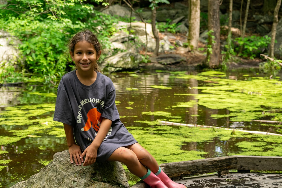 Camper sitting on rock wearing BMB camp shirt