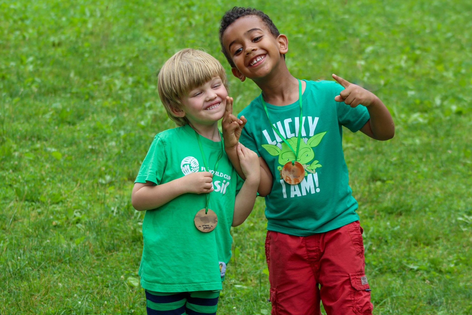 Two friends at Drumlin Farm Camp smiling for the camera in a green field