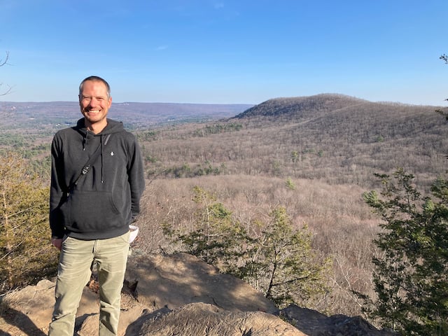 Dr. Nathan Senner standing on a summit overlooking mountains