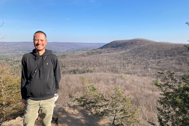 Dr. Nathan Senner standing on a summit overlooking mountains