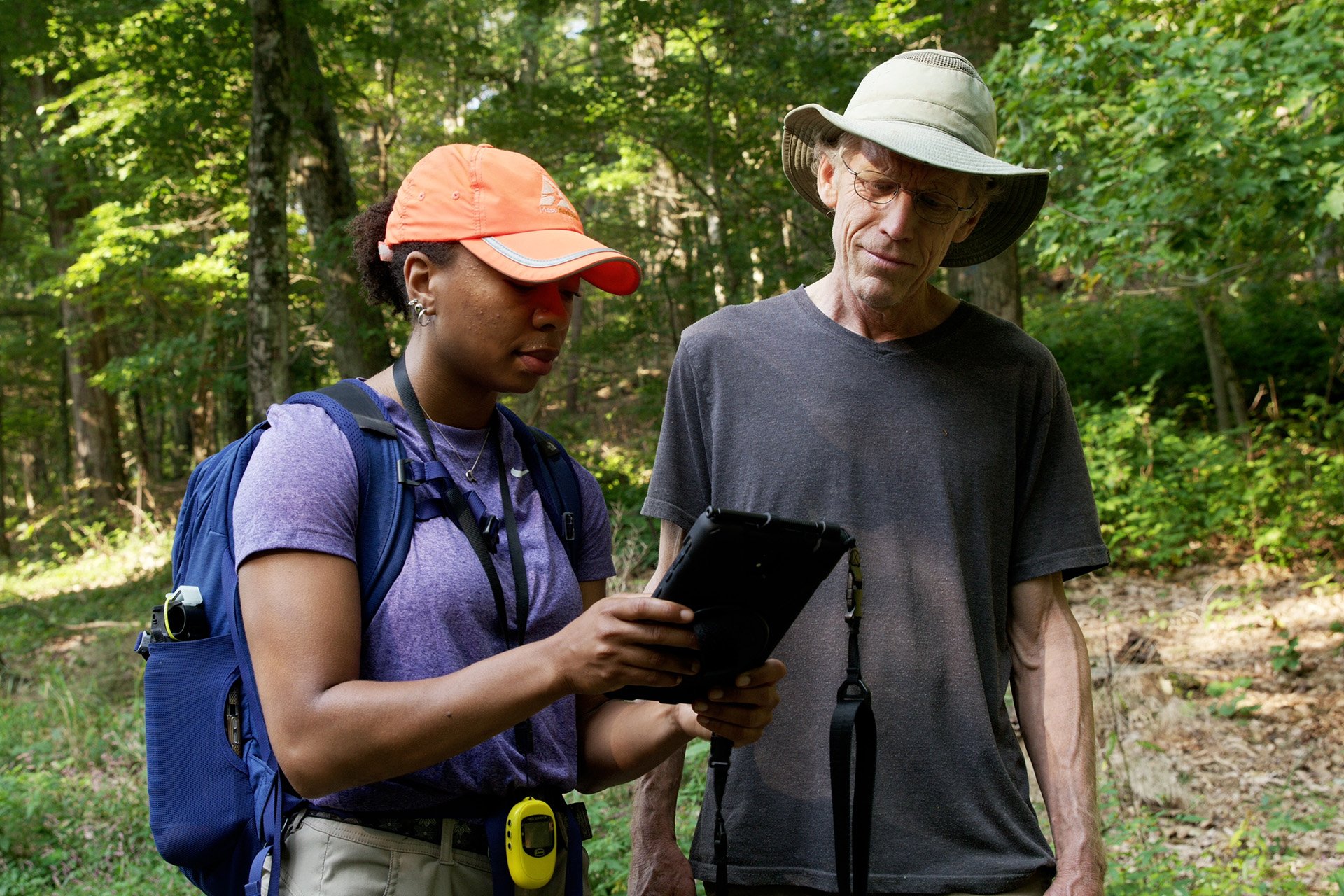 Two people in forest looking at a tablet