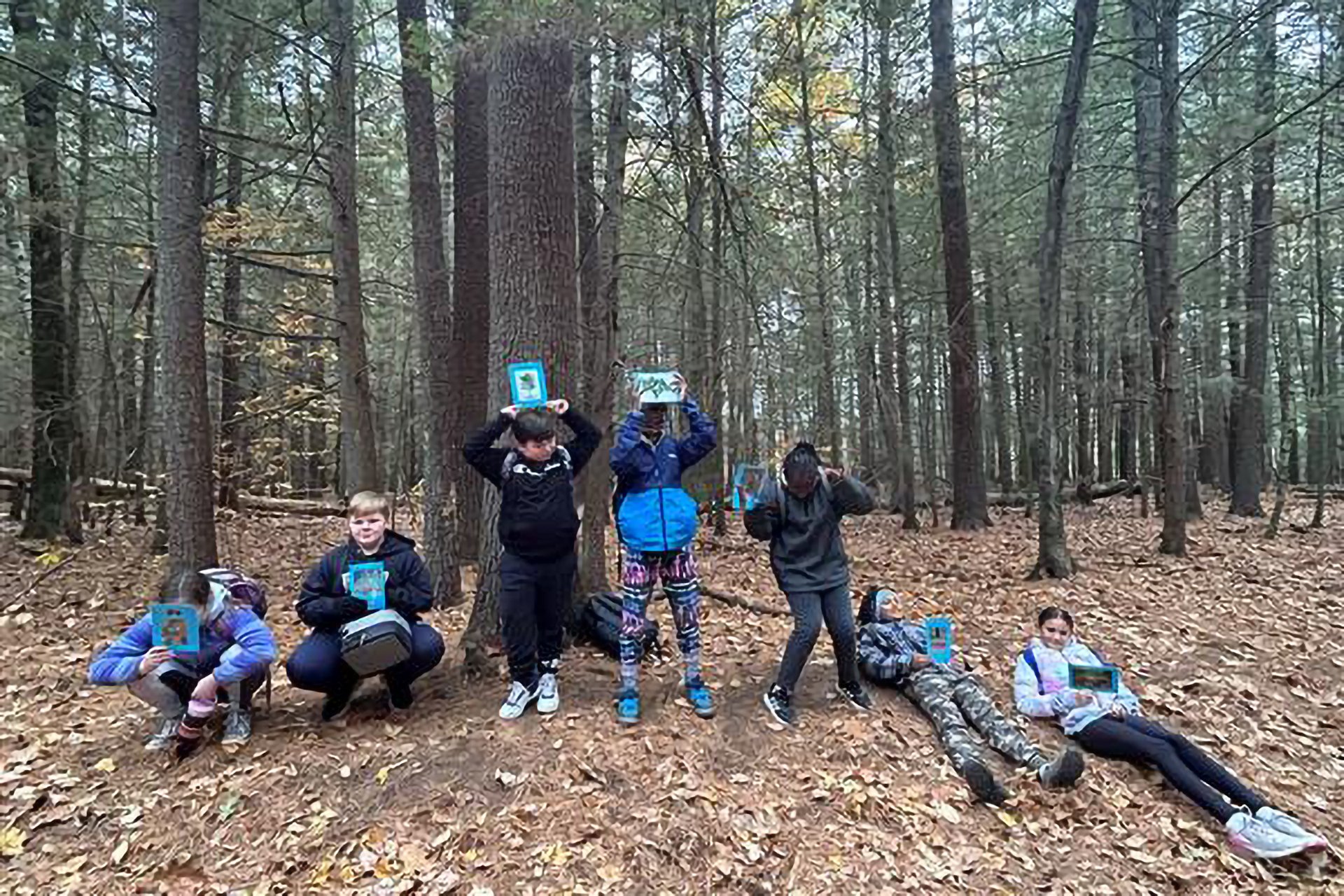 Students showing off their work, standing in the forest