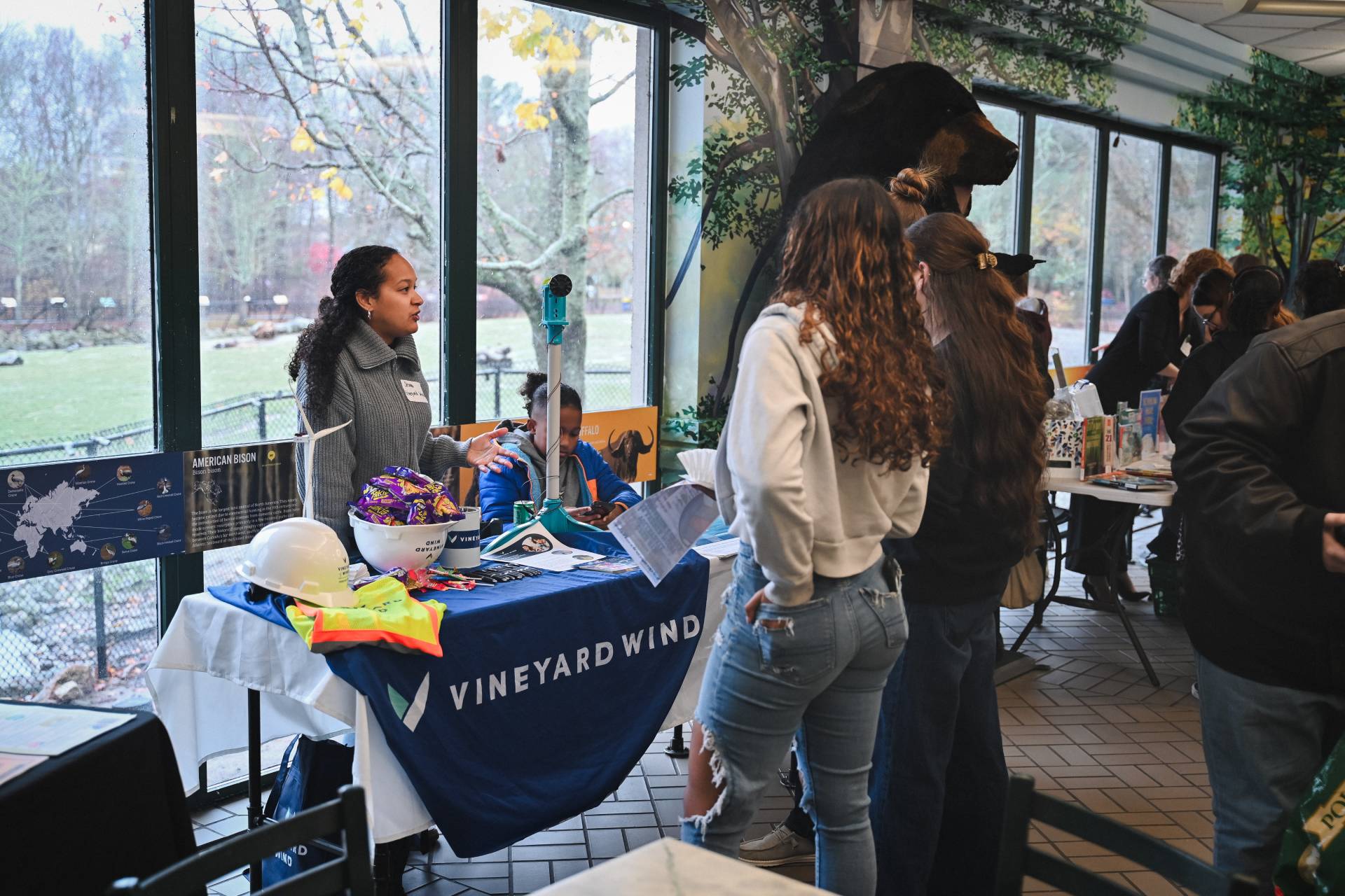 A person behind a table converses with visitors at the South Coast Youth Climate Summit.