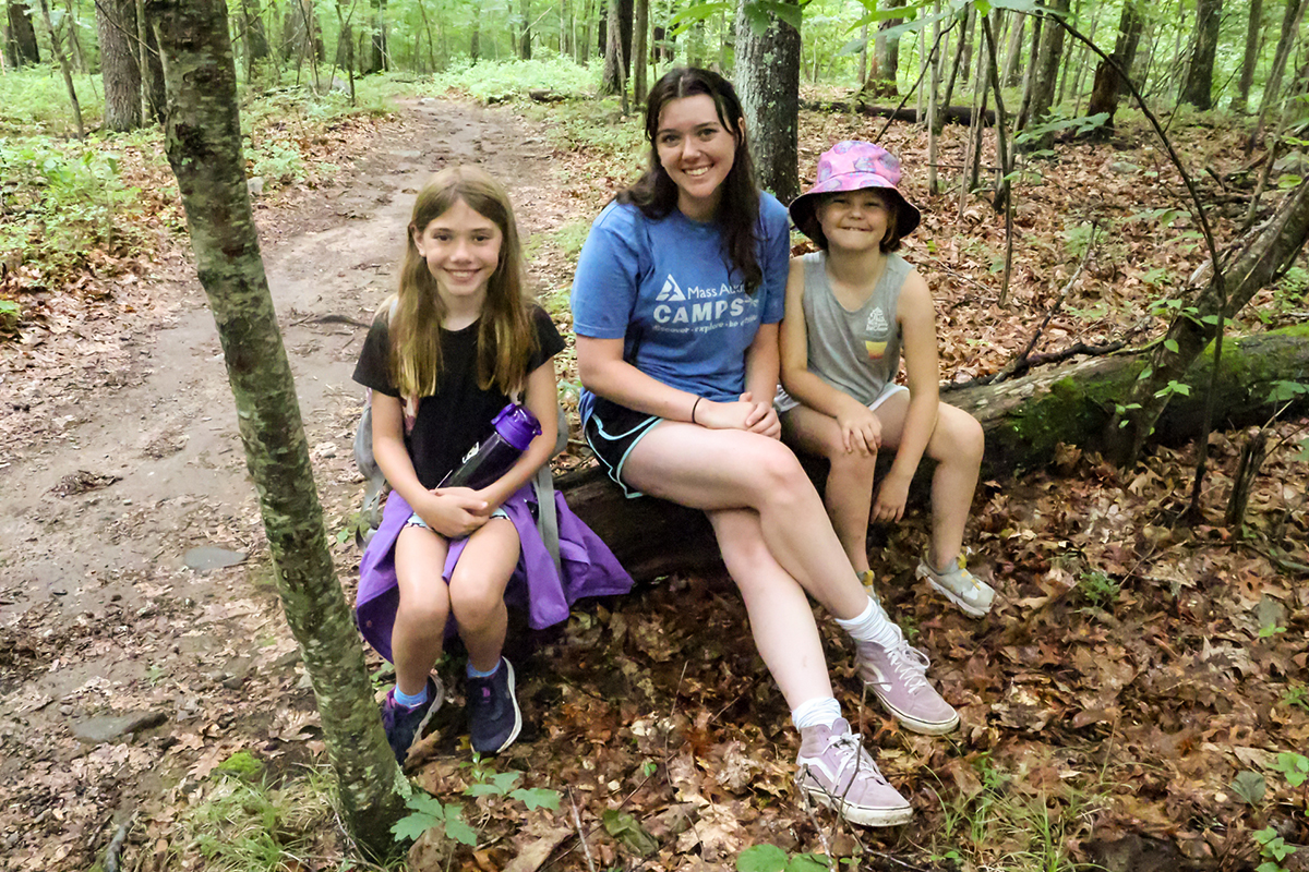 two campers and a counselor in training on a log