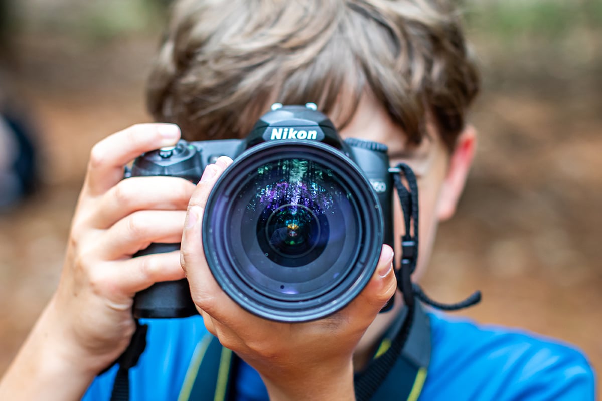 Photo of boy holding an SLR camera up to his eye