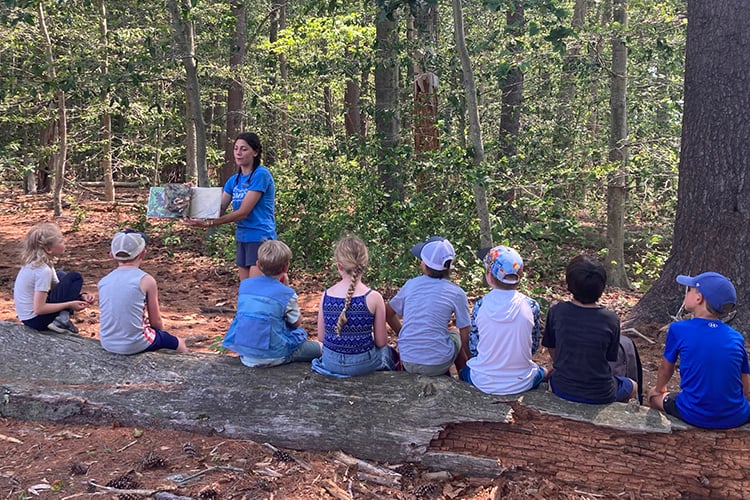 Ipswich River Counselor with Campers Reading on Log