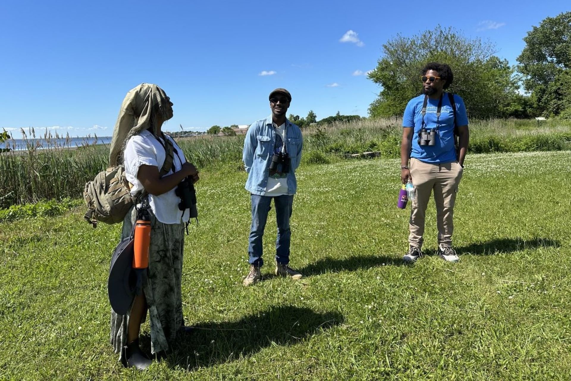 People stand in a field wearing binoculars.