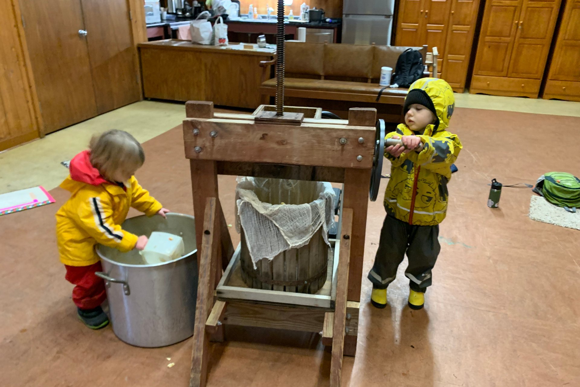 Preschoolers using an old-fashioned apple press and bucket