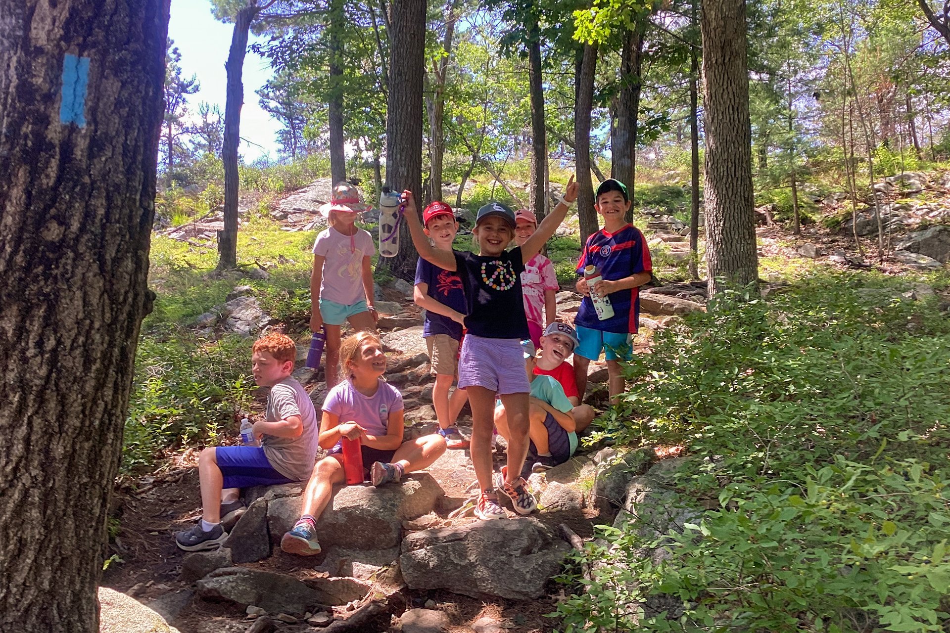 A group of Blue Hills campers pauses for a rest and water break on a steep, rocky hiking trail