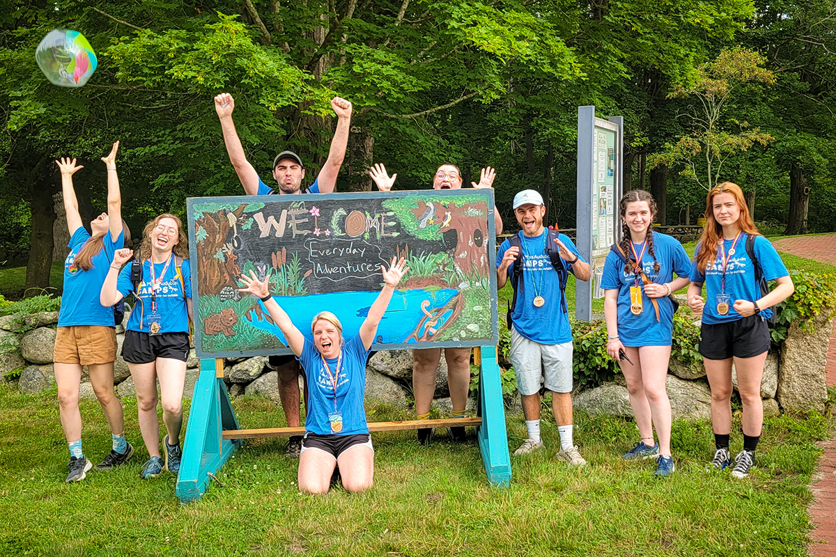 Campp counselors posing in front of a welcome sign