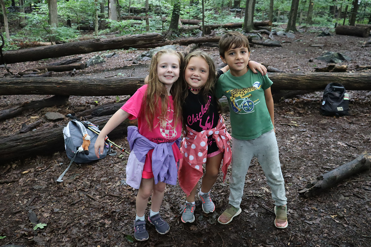 Three young campers in the woods with arms around each other