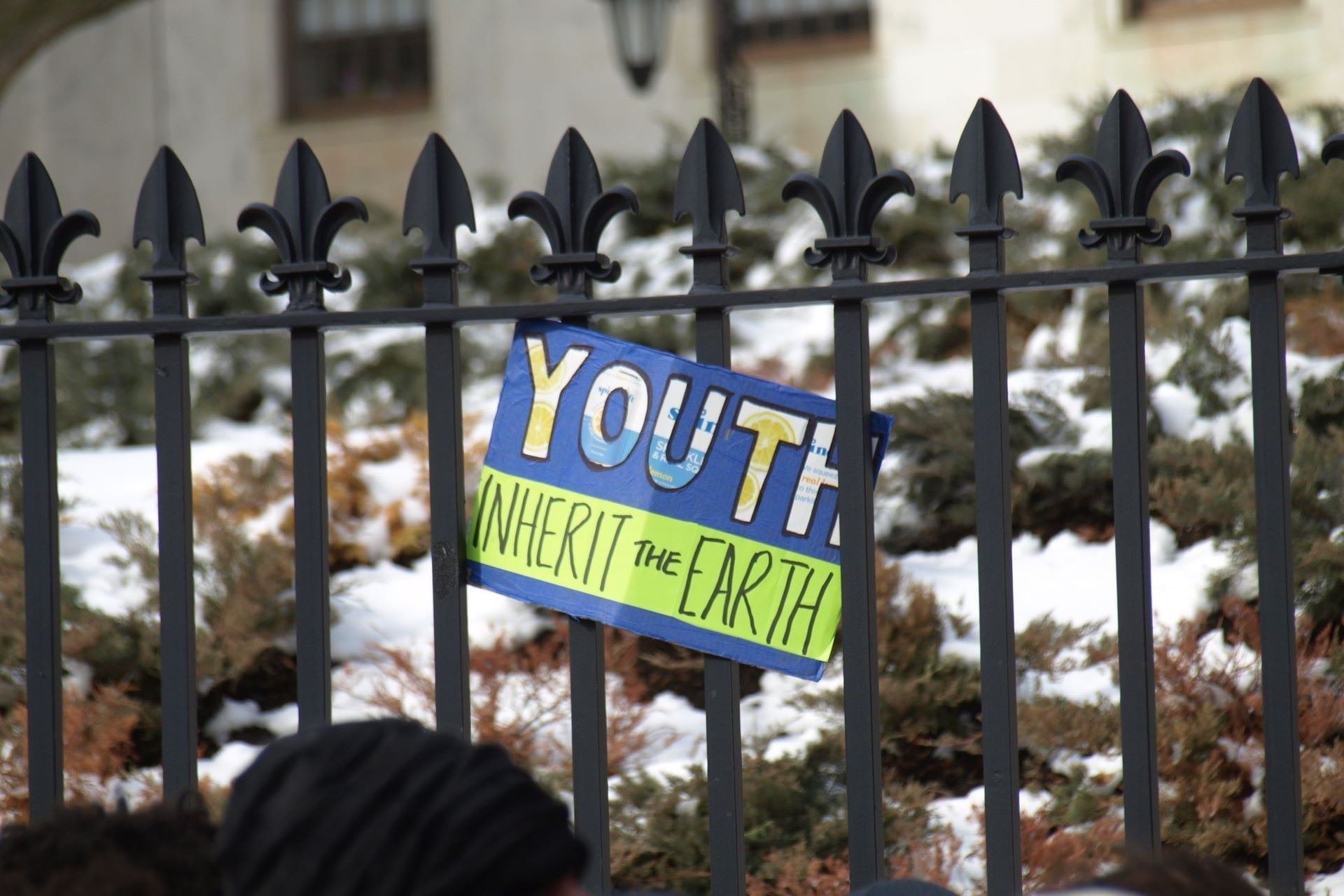 A hand-made sign reads "youth will inherit the earth," hanging on a fence during Youth Climate Lobby Day.