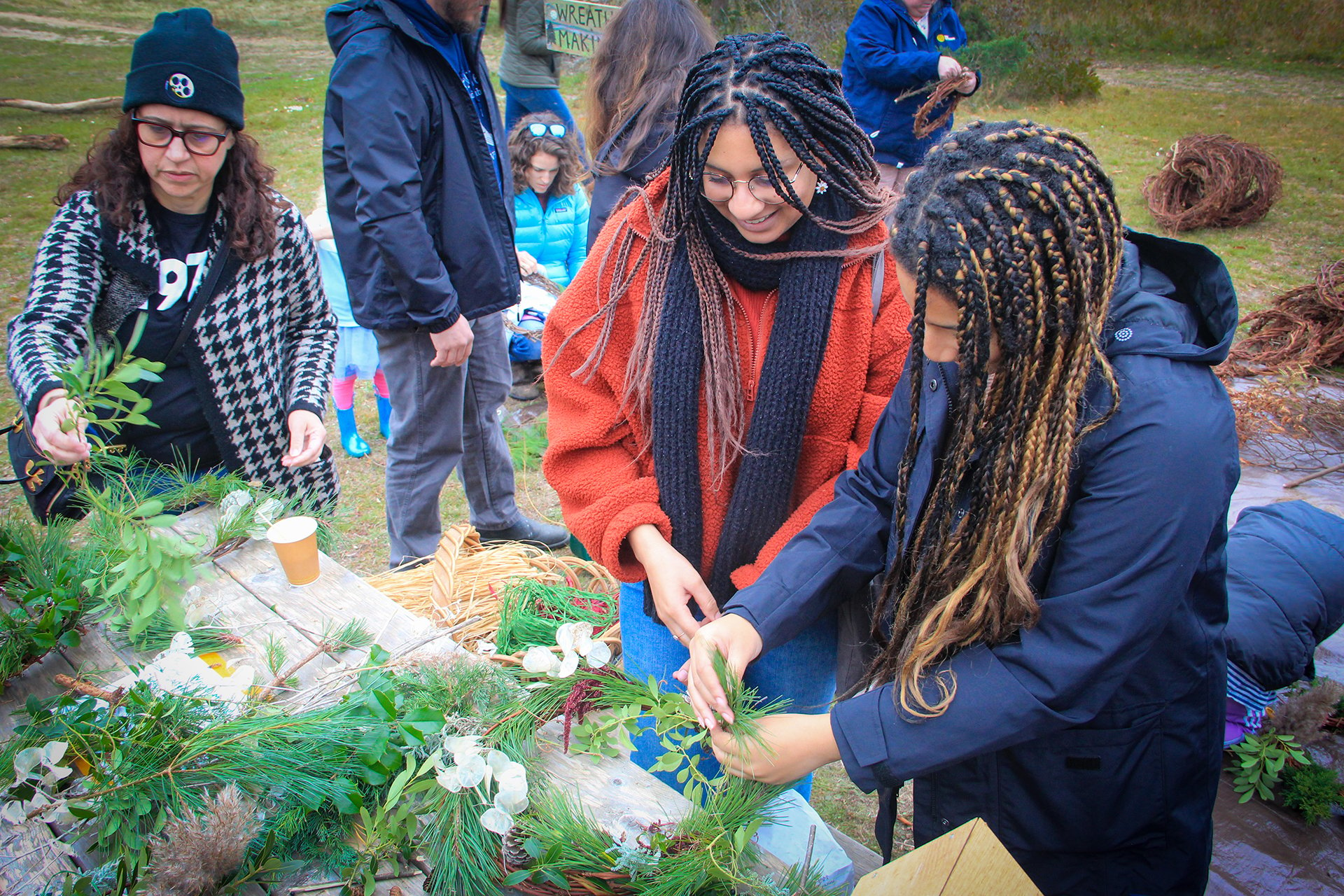 a small group of young adults making a wreath